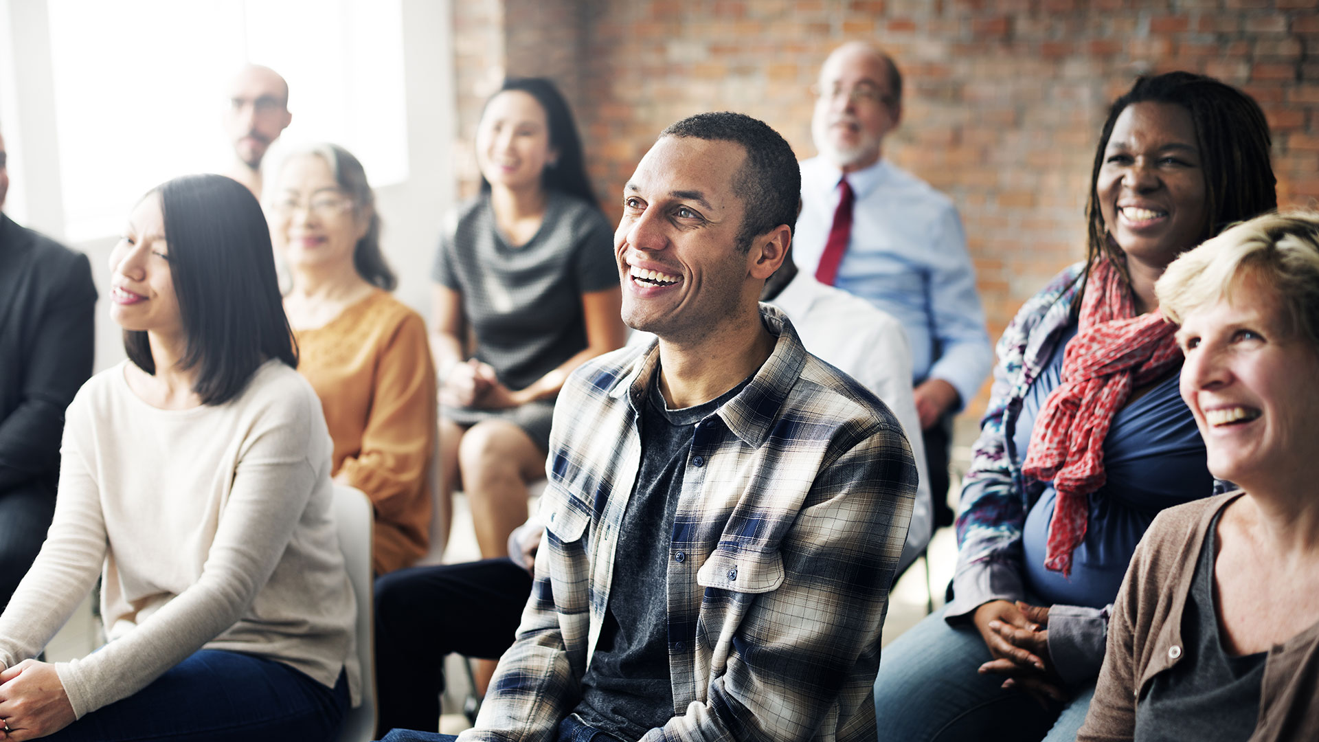 Audience members smiling and engaged during a presentation.