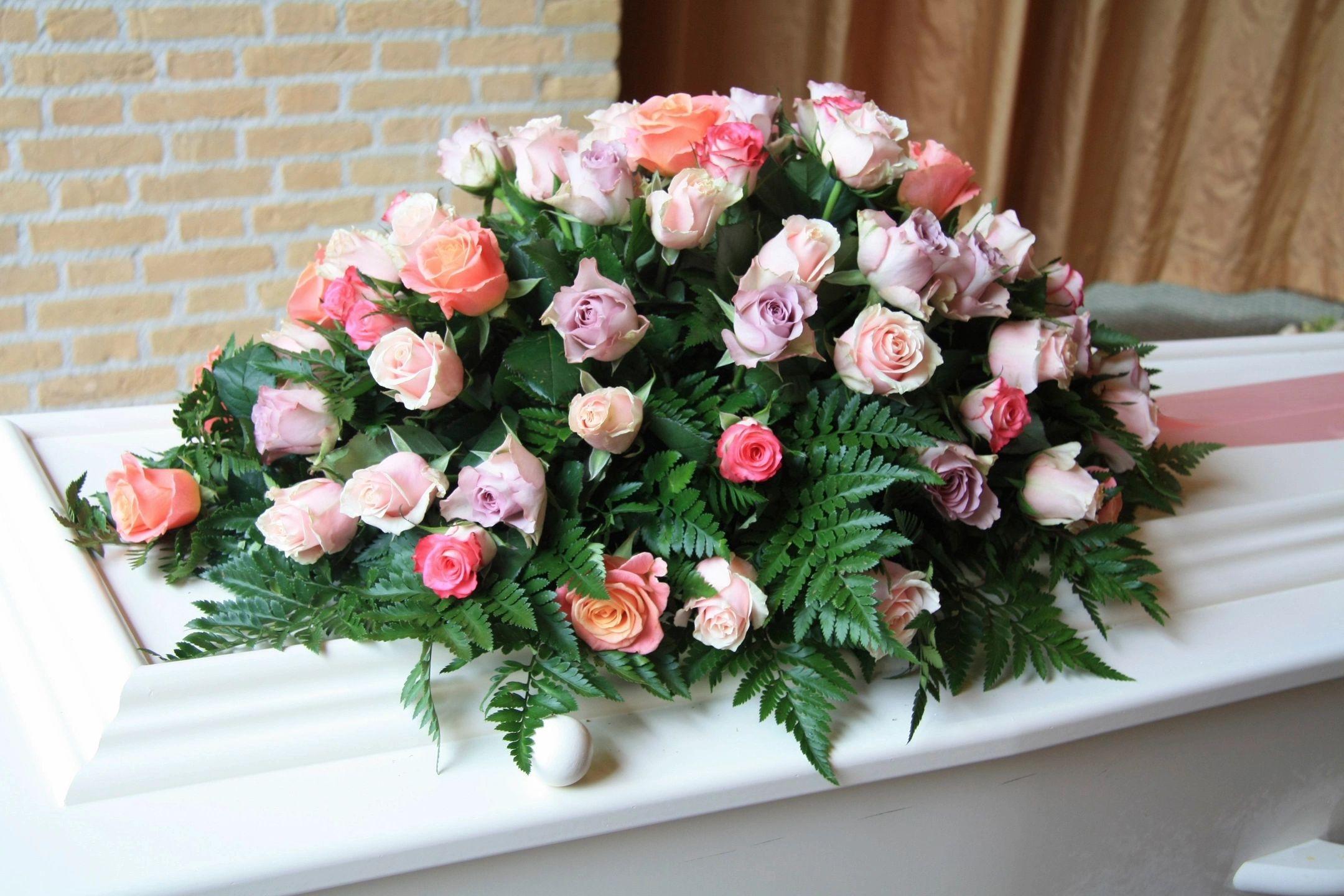 Elegant floral arrangement of pink and peach roses with green foliage.